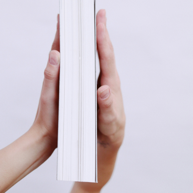 Two hands holding a book examining the thickness.